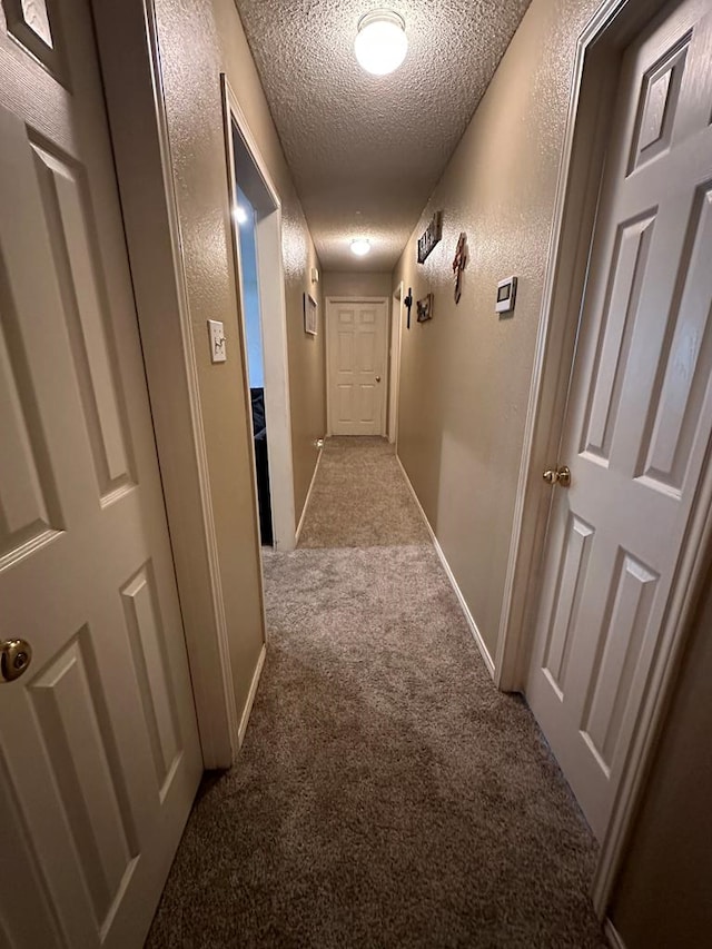 hall with light carpet and a textured ceiling