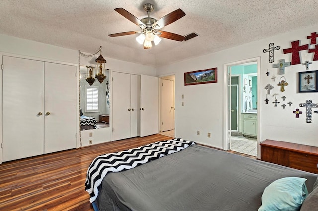 3013 Whittle Way, Midland, TX 79707 - bedroom featuring wood finished floors, two closets, a textured ceiling, ensuite bathroom, and ceiling fan