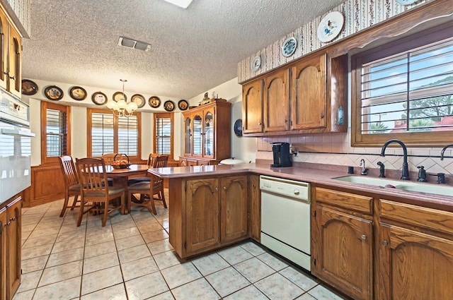 3013 Whittle Way, Midland, TX 79707 - kitchen featuring white appliances, a sink, a peninsula, brown cabinetry, and healthy amount of natural light