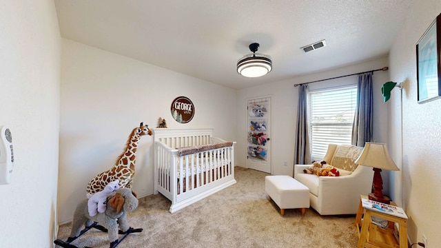 carpeted bedroom featuring a nursery area and a textured ceiling