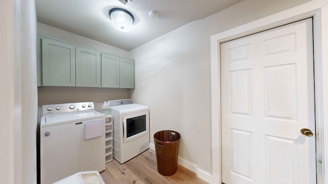 washroom featuring cabinets, a textured ceiling, independent washer and dryer, and light hardwood / wood-style flooring