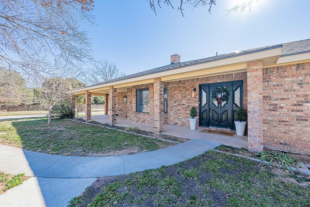 view of exterior entry with a yard and covered porch