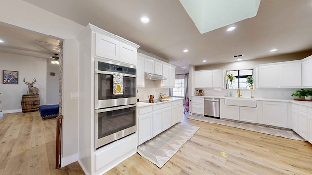 kitchen with sink, light hardwood / wood-style flooring, white cabinets, and appliances with stainless steel finishes