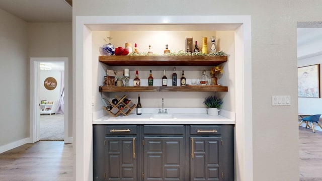 bar featuring sink, gray cabinets, and light hardwood / wood-style floors