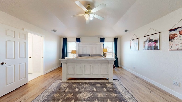 bedroom with ceiling fan, lofted ceiling, a textured ceiling, and light hardwood / wood-style floors