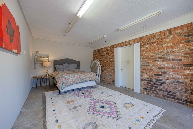 bedroom with a wall mounted air conditioner, concrete flooring, a textured ceiling, and brick wall