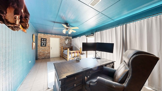 tiled home office with ceiling fan and brick wall