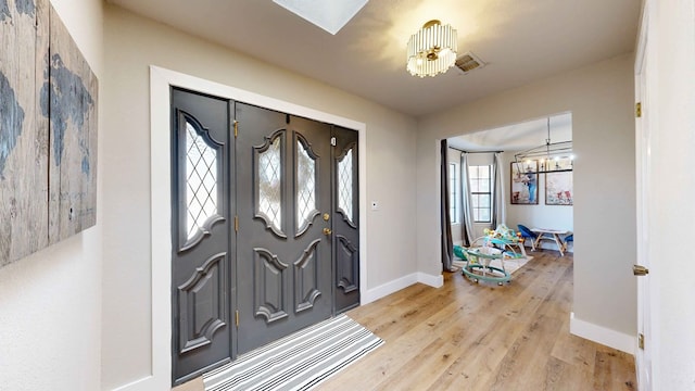 foyer with a notable chandelier and light hardwood / wood-style flooring