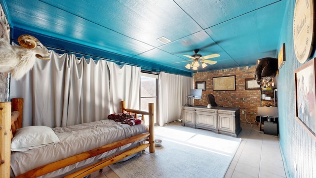 tiled bedroom featuring ceiling fan and brick wall