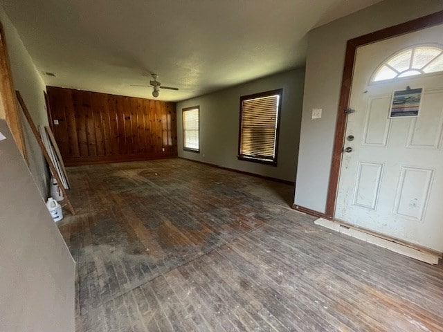 entryway with wood walls, a ceiling fan, baseboards, and hardwood / wood-style floors