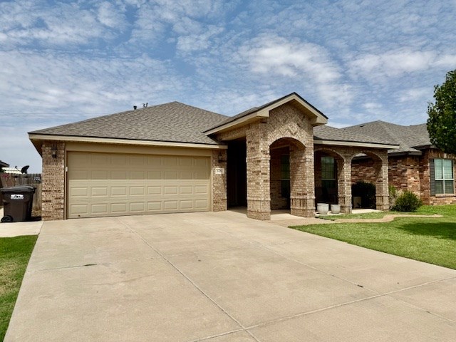 1406 Wrangler Ln, Midland, TX 79705 - view of front of property featuring brick siding, concrete driveway, an attached garage, a front lawn, and a shingled roof
