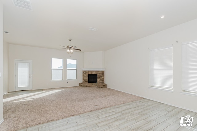 unfurnished living room featuring a ceiling fan, visible vents, light carpet, a brick fireplace, and baseboards