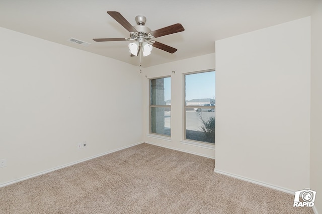 empty room featuring visible vents, baseboards, a ceiling fan, and light carpet