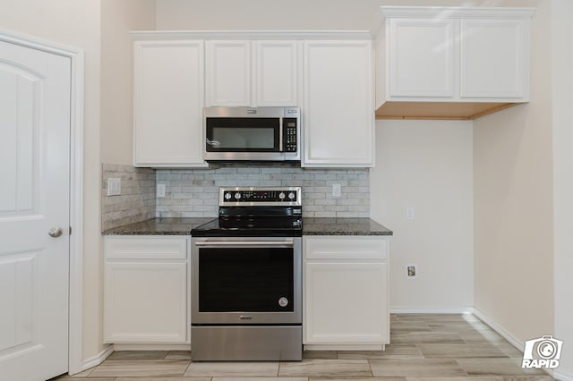 kitchen featuring dark stone countertops, white cabinetry, backsplash, and stainless steel appliances