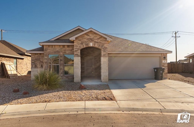view of front facade with a garage, a shingled roof, fence, stone siding, and concrete driveway