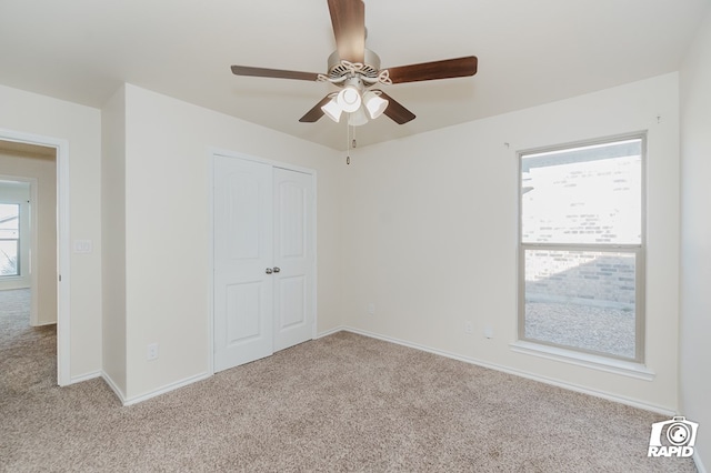 unfurnished bedroom featuring carpet, a closet, baseboards, and ceiling fan