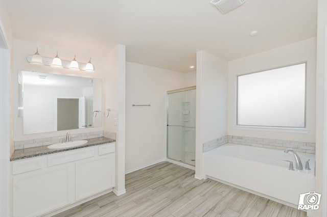 bathroom with a garden tub, a shower stall, vanity, visible vents, and wood finished floors