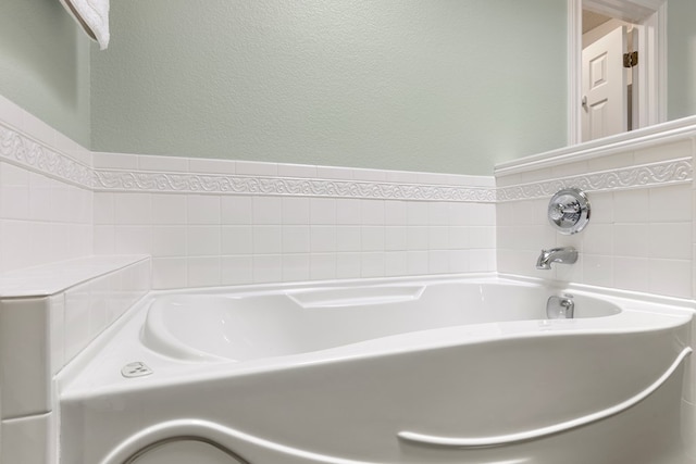 full bathroom with a textured wall and a garden tub