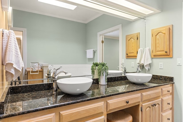 full bath featuring double vanity, crown molding, and a sink
