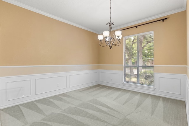spare room featuring carpet floors, a decorative wall, a chandelier, a wainscoted wall, and crown molding