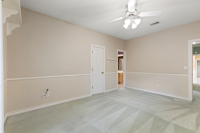 empty room featuring carpet flooring, a ceiling fan, visible vents, and baseboards