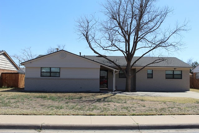 view of front of home featuring brick siding, fence, and a front yard