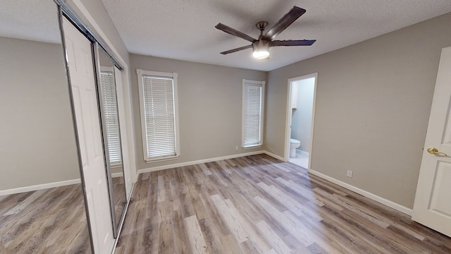 3608 Apollo Ct, Midland, TX 79707 - unfurnished bedroom with light wood-type flooring, a textured ceiling, a closet, baseboards, and ensuite bathroom