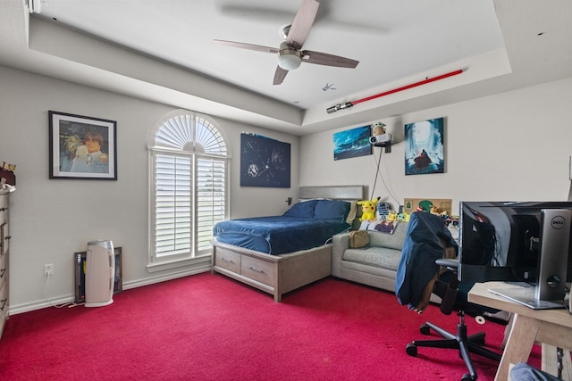 carpeted bedroom featuring a raised ceiling and ceiling fan