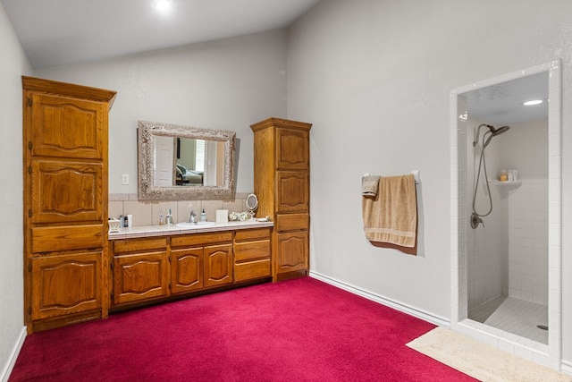 bathroom with vanity, lofted ceiling, and a tile shower