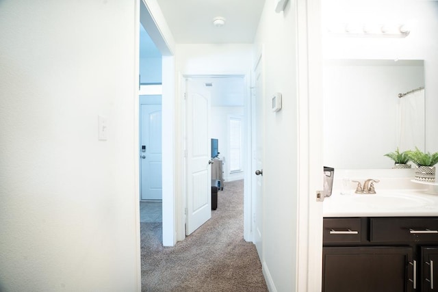 hallway with a sink and light carpet