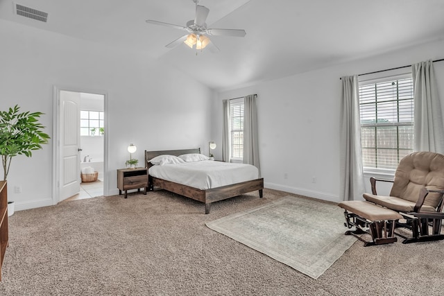 bedroom with multiple windows, light colored carpet, vaulted ceiling, baseboards, and ensuite bathroom