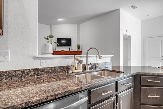 kitchen featuring a sink, dark brown cabinetry, dishwasher, and dark stone countertops