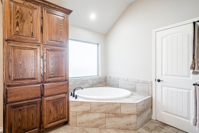 full bath with lofted ceiling, a garden tub, and tile patterned flooring