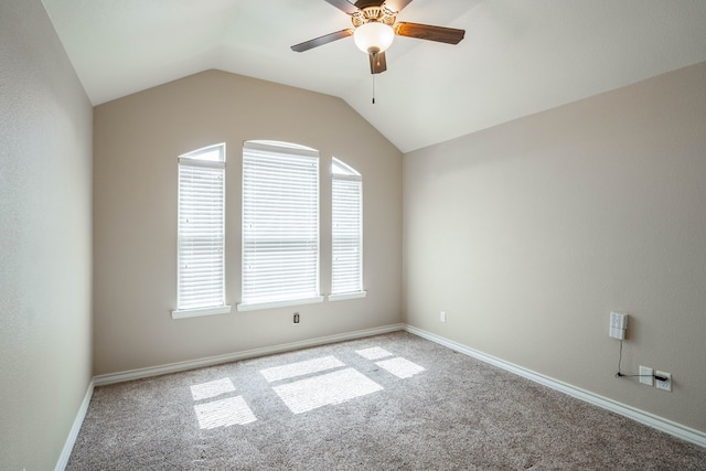 empty room featuring lofted ceiling, baseboards, ceiling fan, and carpet