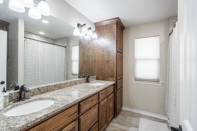 full bath with double vanity, baseboards, and a sink