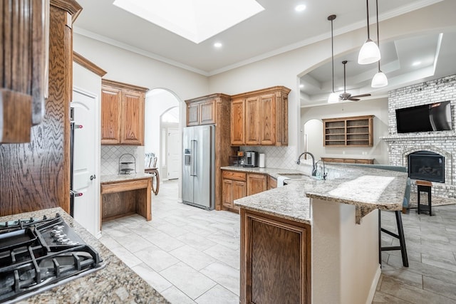 kitchen with high end refrigerator, open floor plan, a sink, a peninsula, and a kitchen bar