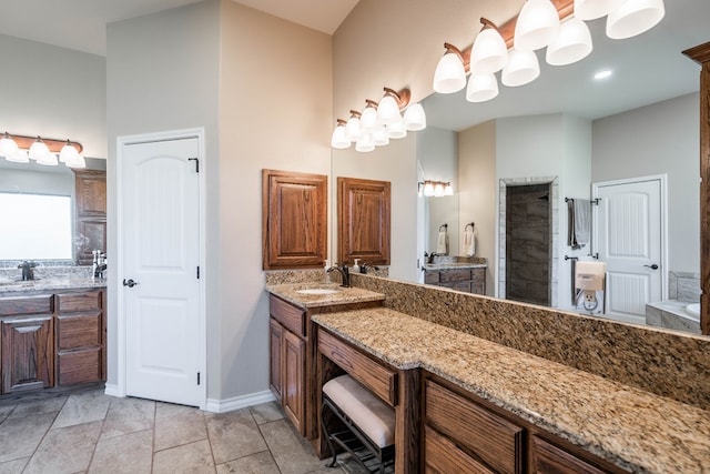 bathroom featuring tile patterned flooring, a tile shower, vanity, and baseboards