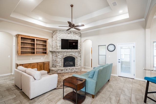 living room featuring a raised ceiling, visible vents, a fireplace, and baseboards