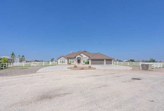 view of front of house featuring a garage, a rural view, fence, and driveway