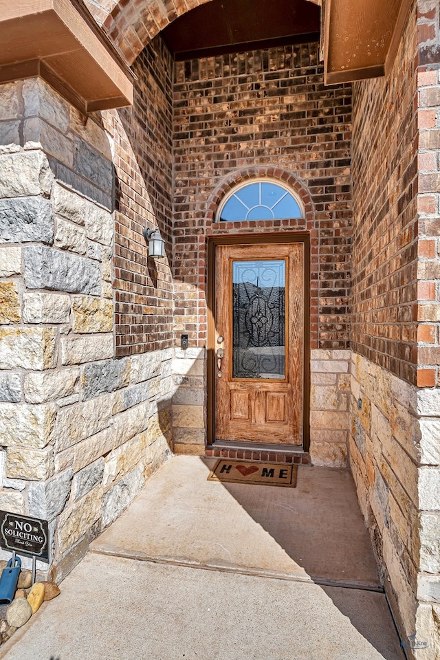 view of exterior entry featuring brick siding