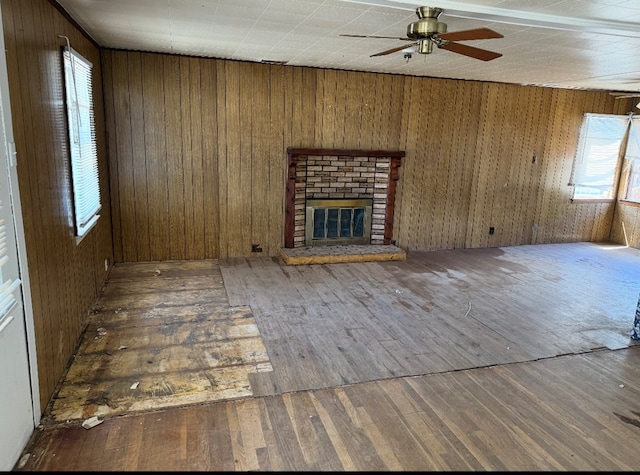 unfurnished living room with wood walls, a fireplace, a ceiling fan, and wood-type flooring