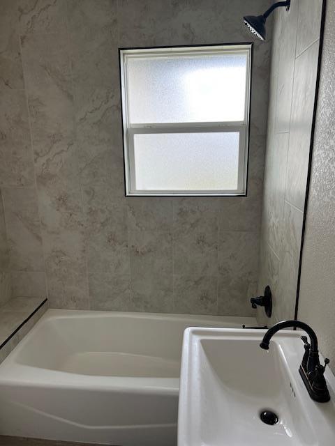 bathroom featuring washtub / shower combination and sink