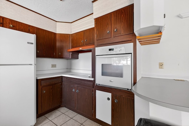 4709 Shadylane Dr, Midland, TX 79703 - kitchen with white appliances, light countertops, a textured ceiling, under cabinet range hood, and light tile patterned floors