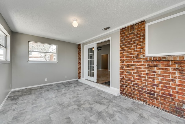 spare room with a textured ceiling, plenty of natural light, and baseboards