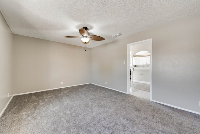 carpeted empty room featuring a ceiling fan, baseboards, and a textured ceiling