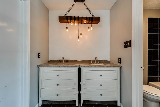 bathroom featuring toilet, double vanity, and a textured ceiling