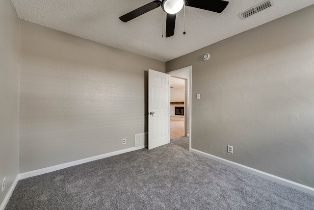 unfurnished room featuring carpet floors, ceiling fan, baseboards, and a textured ceiling