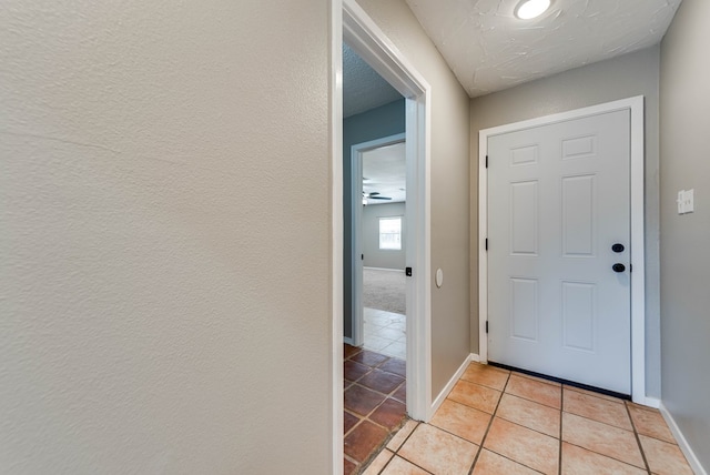 doorway featuring baseboards and light tile patterned floors