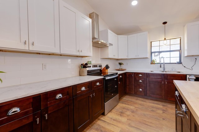 kitchen with pendant lighting, wall chimney range hood, sink, appliances with stainless steel finishes, and white cabinetry