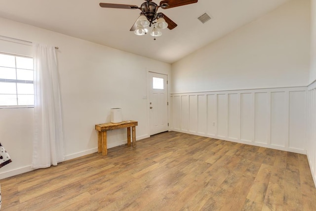 empty room with ceiling fan, lofted ceiling, light hardwood / wood-style flooring, and a wealth of natural light